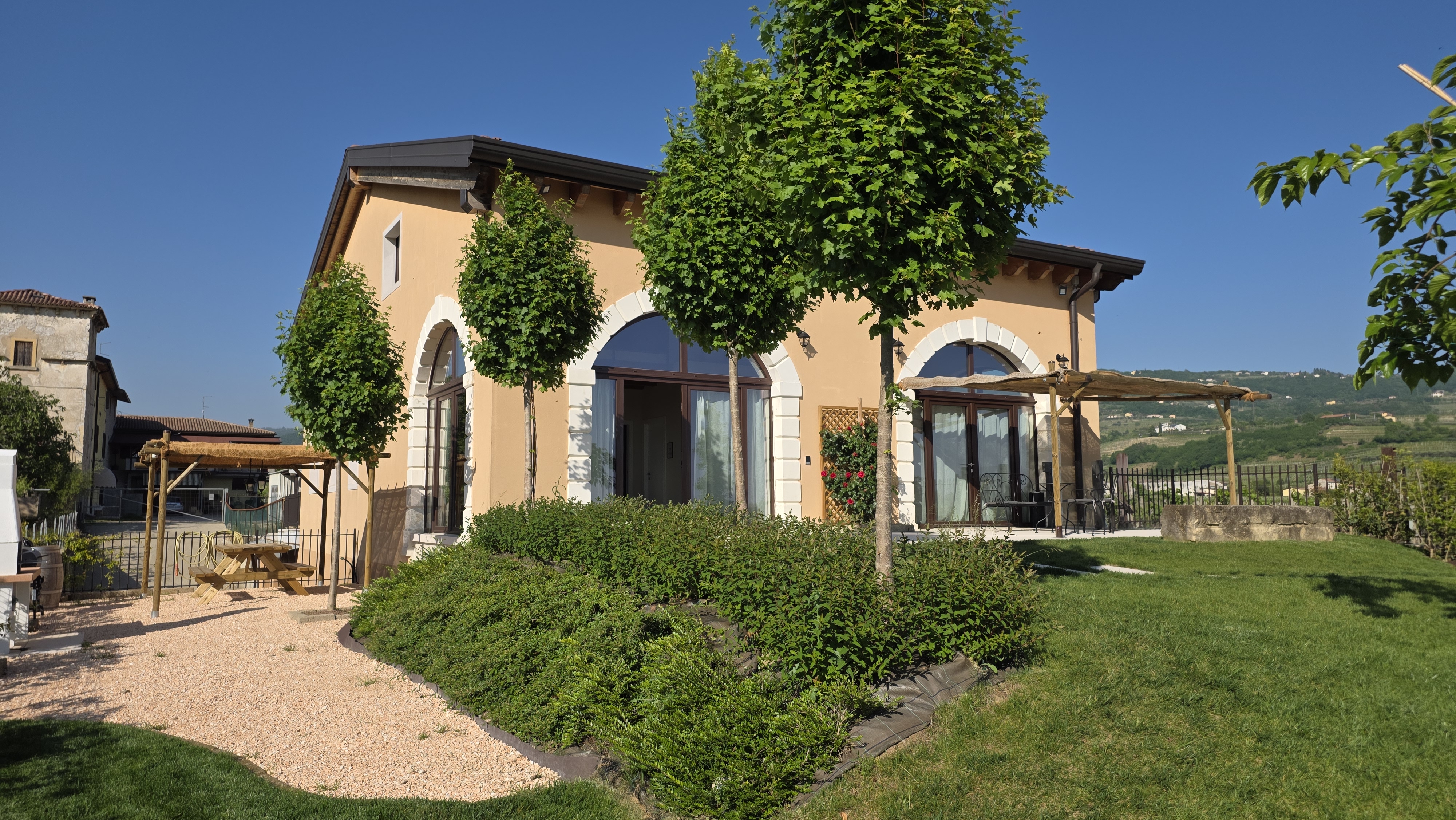 Facciata di Agriturismo Igino con giardino curato e vigneti sullo sfondo